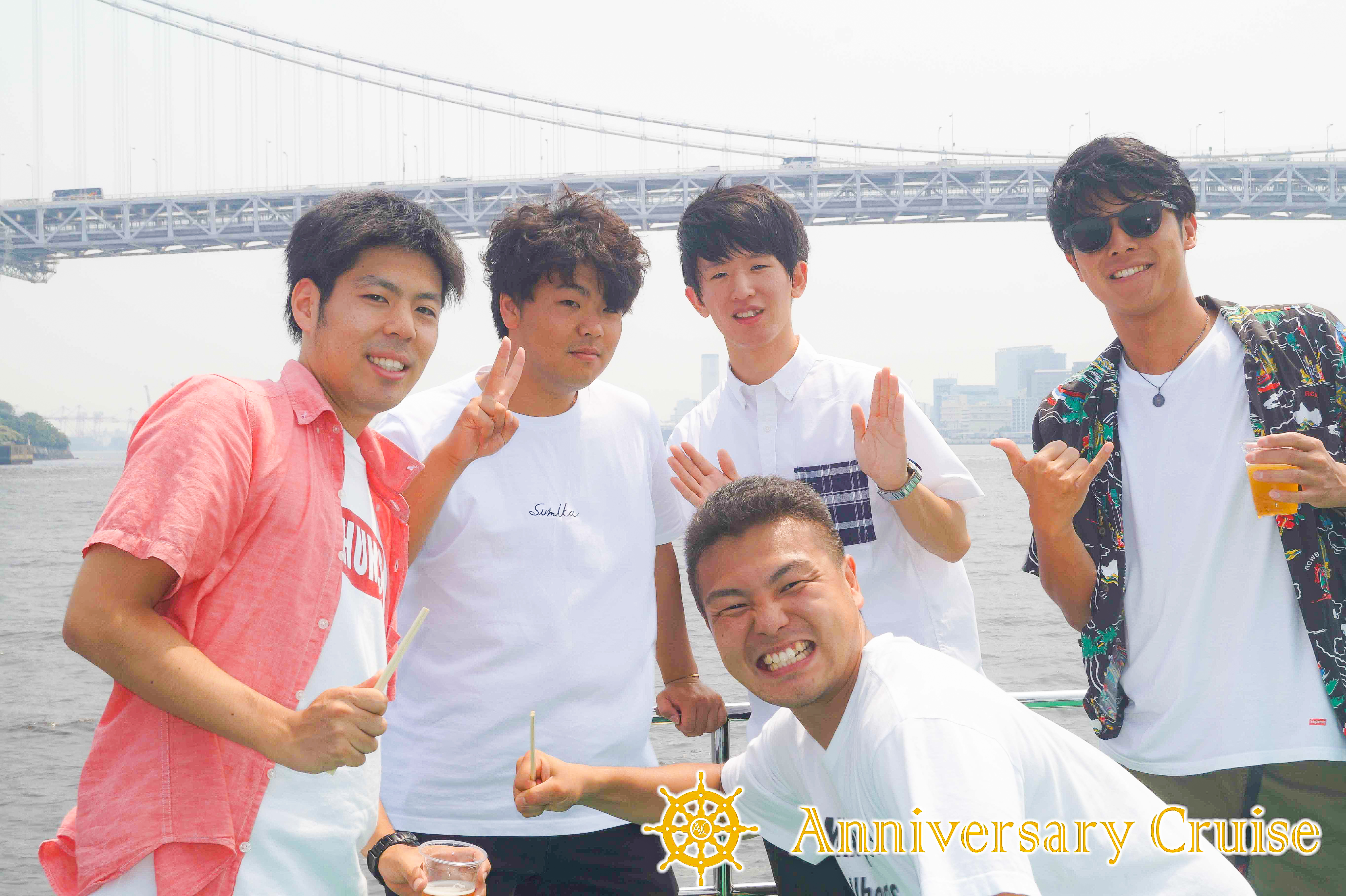 レインボーブリッジを背景に記念写真を撮る男性グル―プ