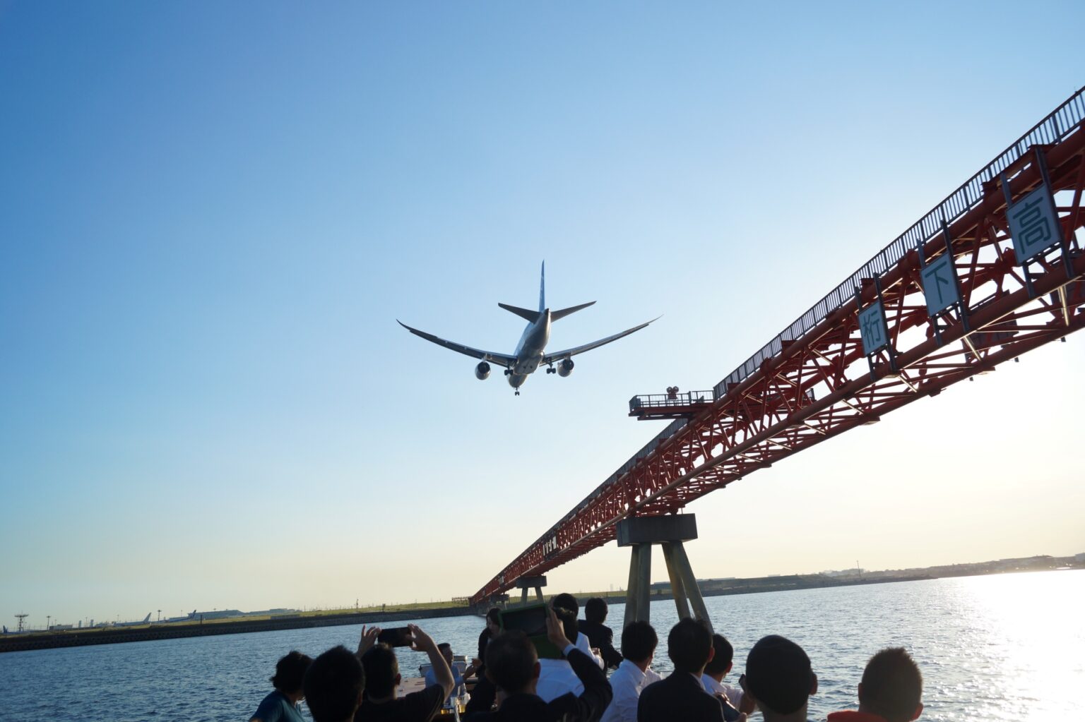 羽田空港沖で船上から飛行機の着陸を見る一行