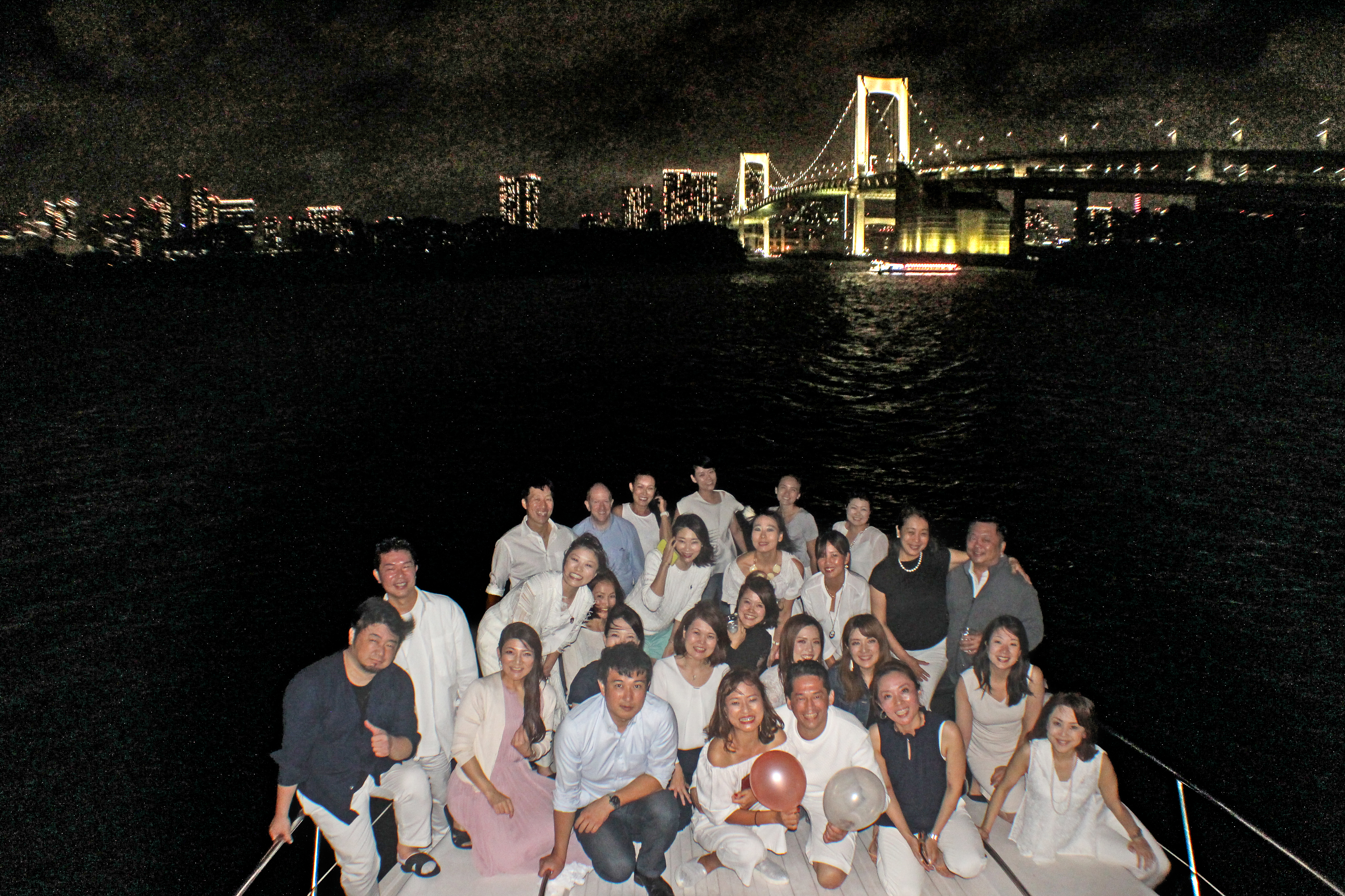 クルーザーのデッキでレインボーブリッジをバックに記念写真