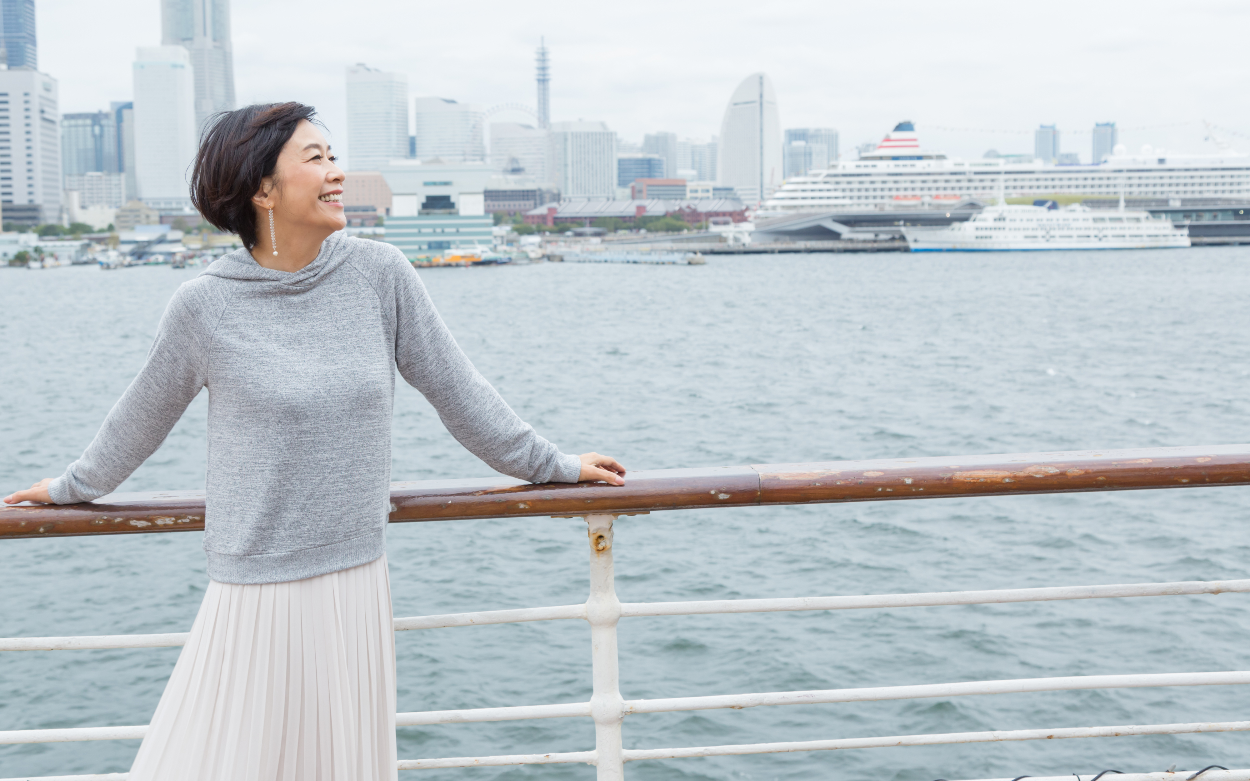 クルーズ船のデッキで風にあたる女性
