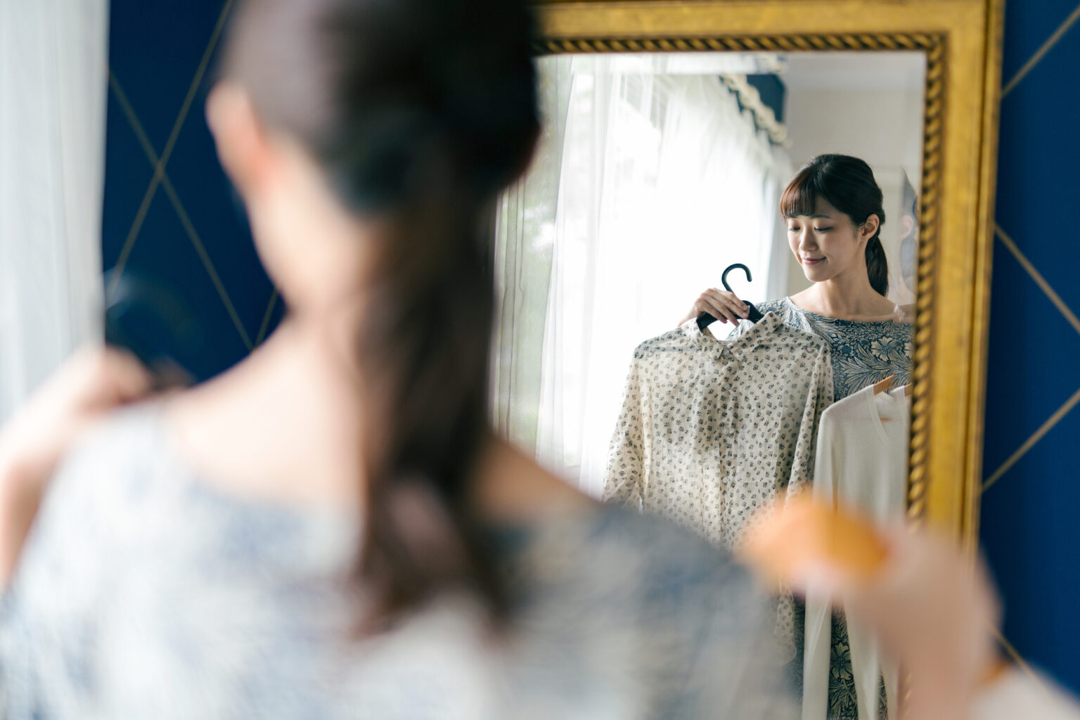 鏡の前で洋服を合わせる女性
