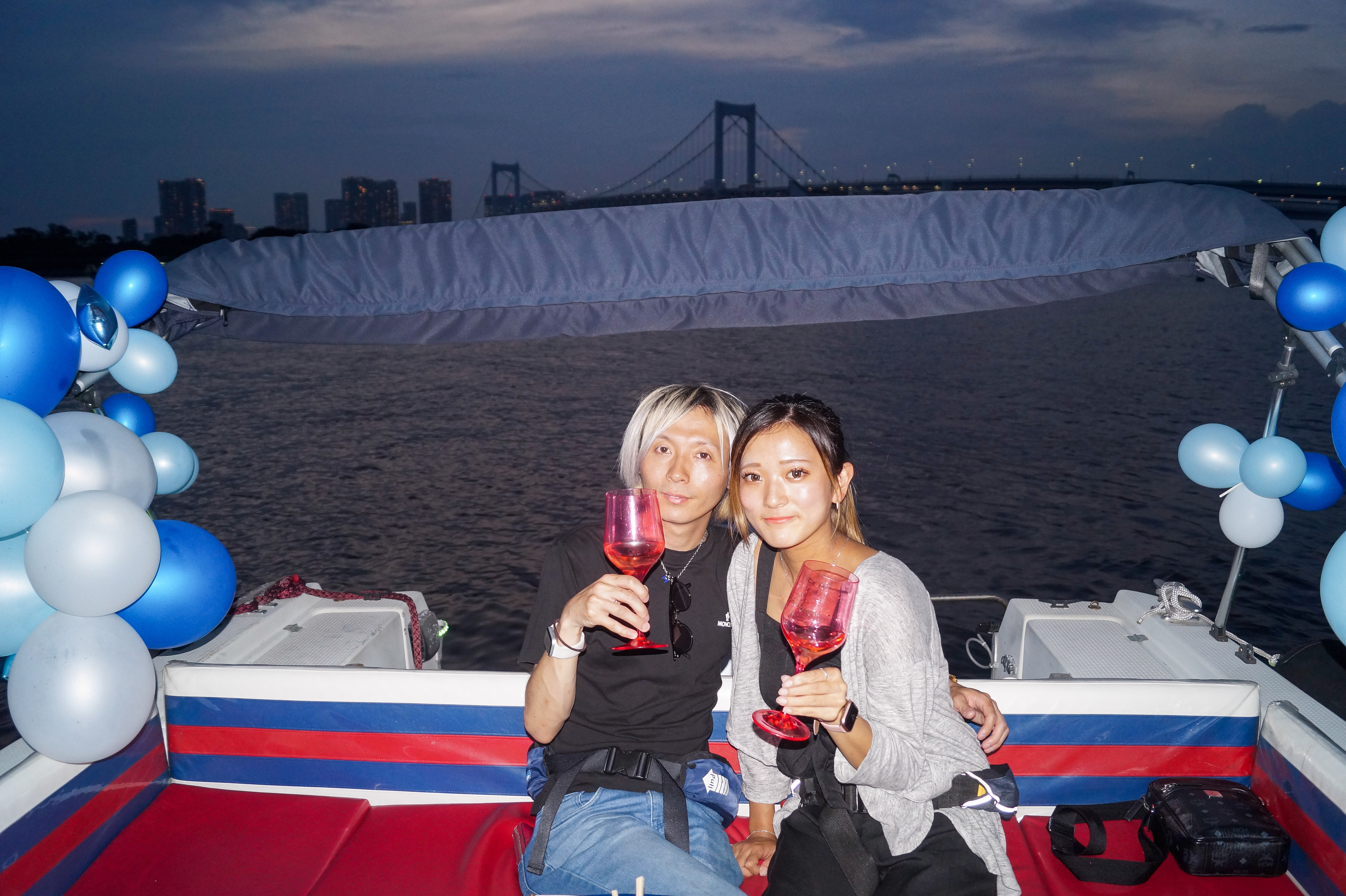 バルーン装飾されたクルーザーで乾杯するカップル