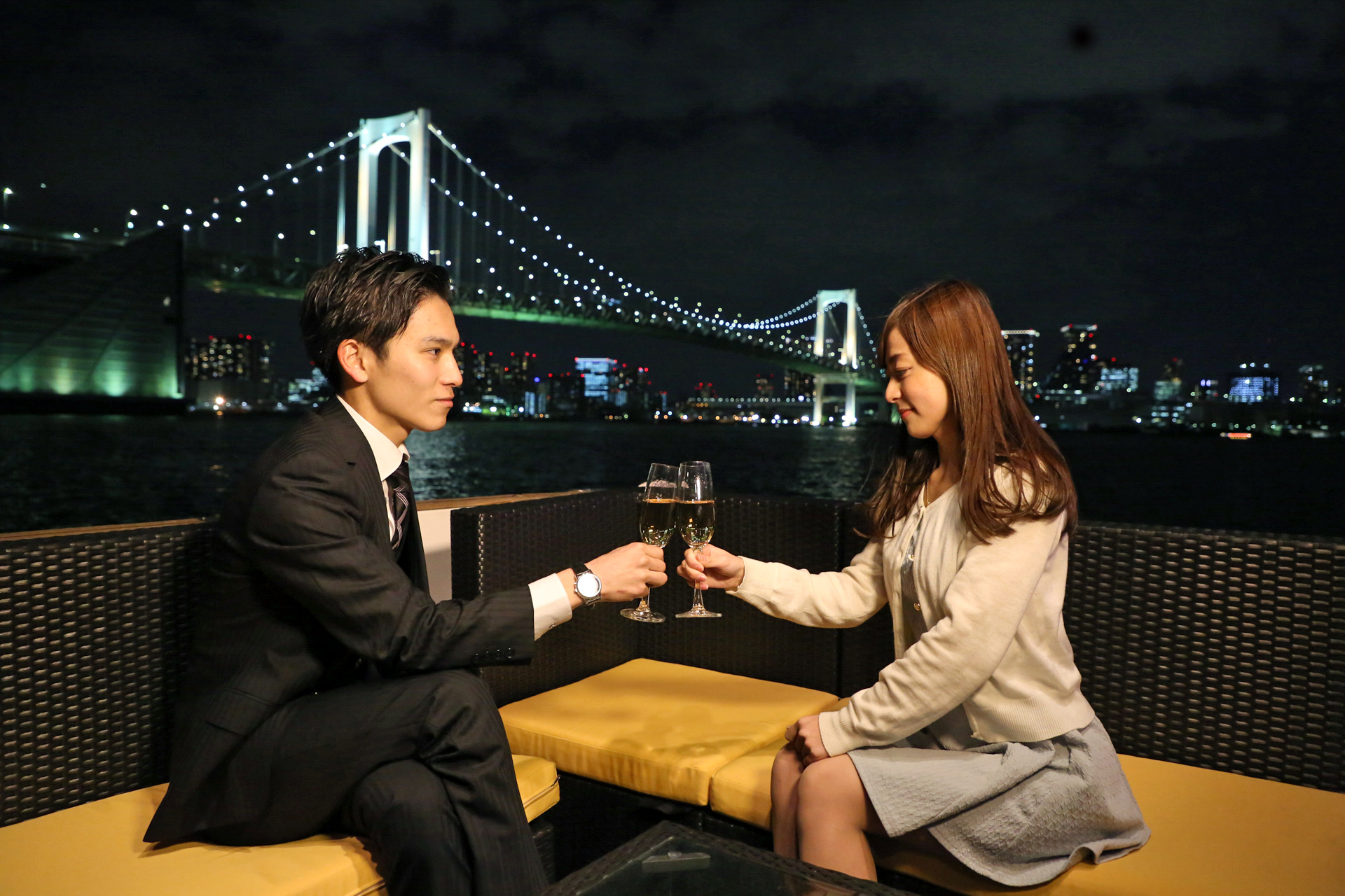 レインボーブリッジをバックに、船の上で乾杯するカップル