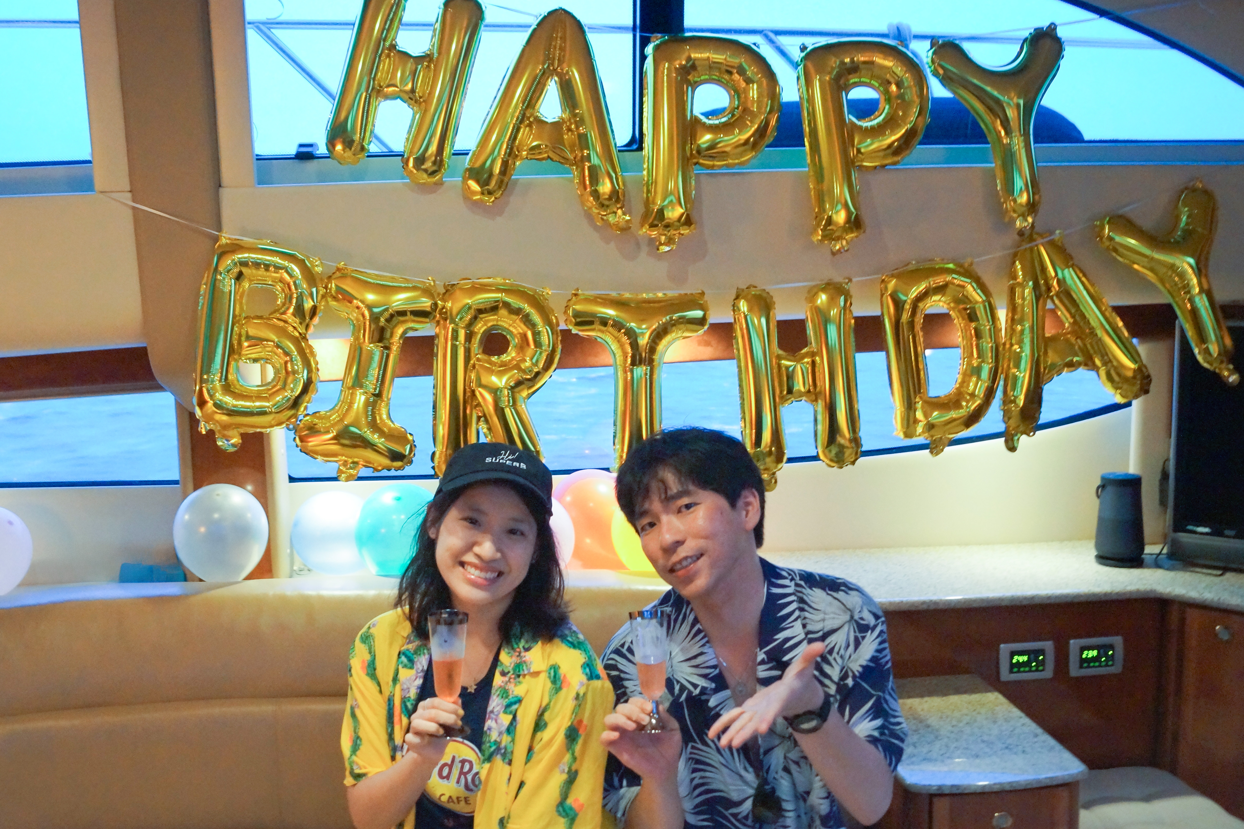 誕生日のバルーン装飾が施された船内で乾杯するカップル