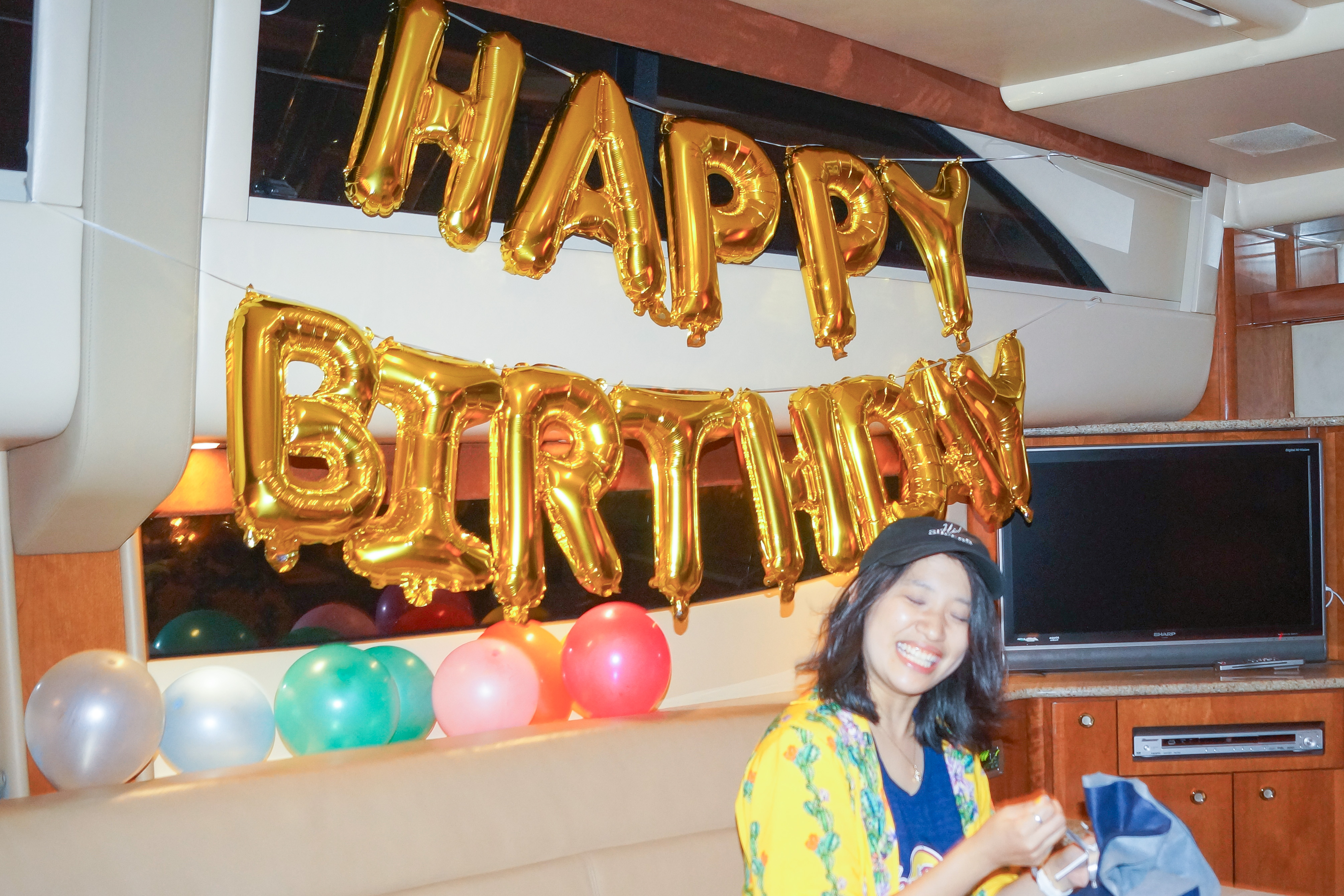 誕生日のバルーン装飾が施された船内でプレゼントを開封する女性