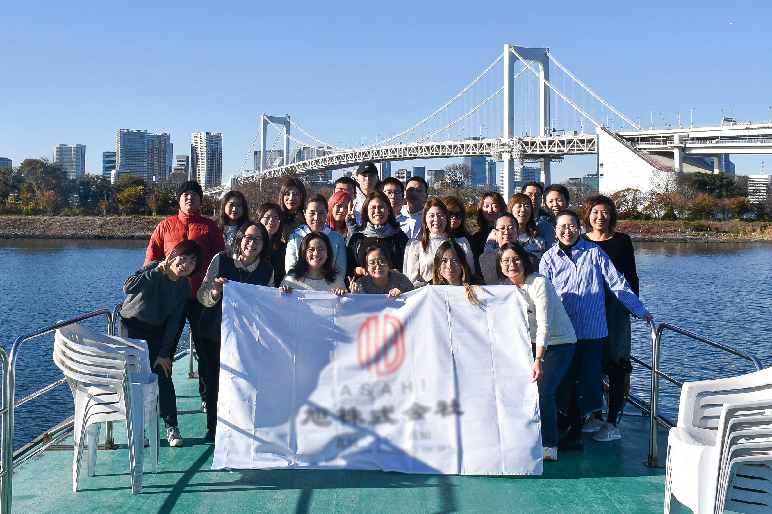 レインボーブリッジをバックに横断幕を持って集合写真