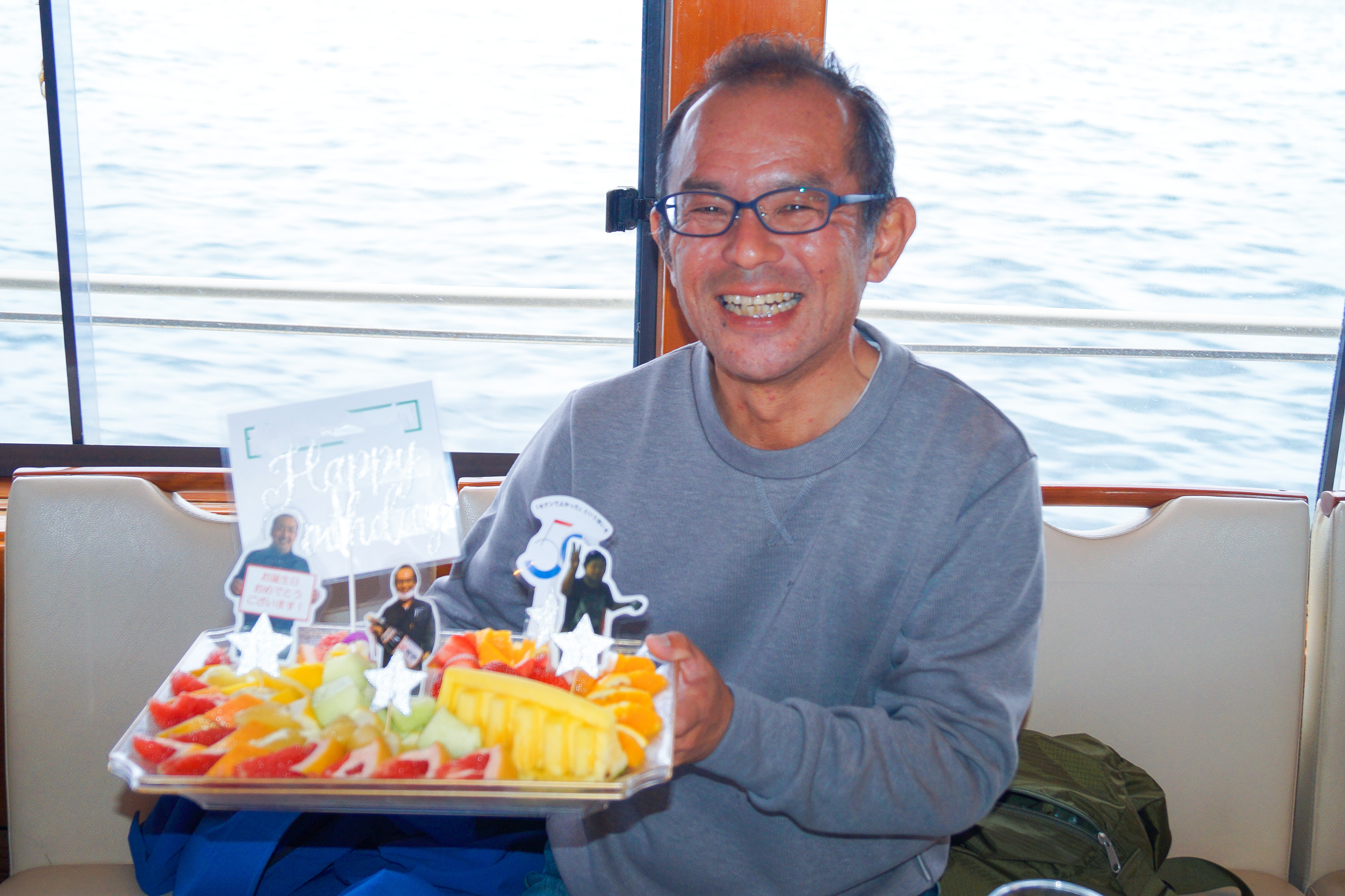 誕生日プレート付きフルーツ盛り合わせを抱える男性