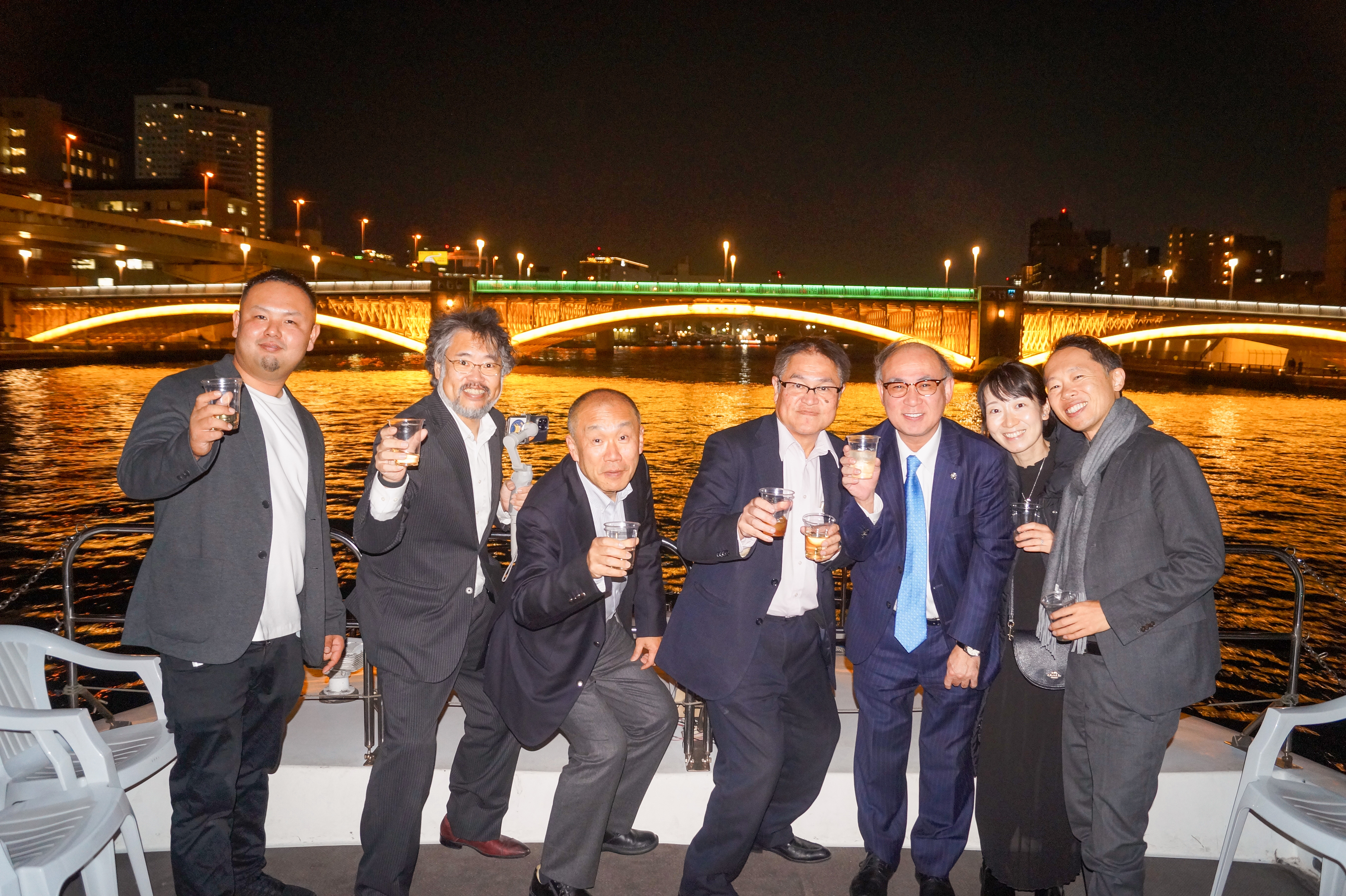 橋をバックに記念写真をとるスーツの男性